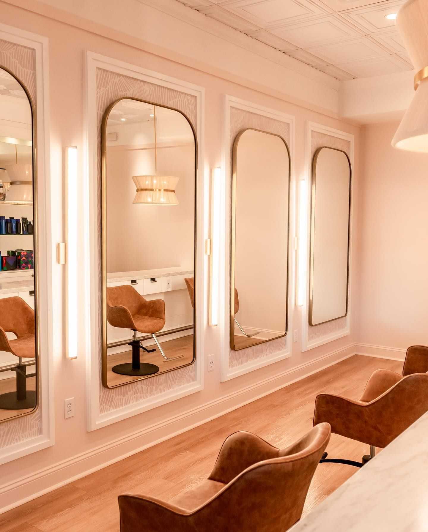 Elegant salon mirrors with warm lighting and plush chairs in a chic, modern setting.