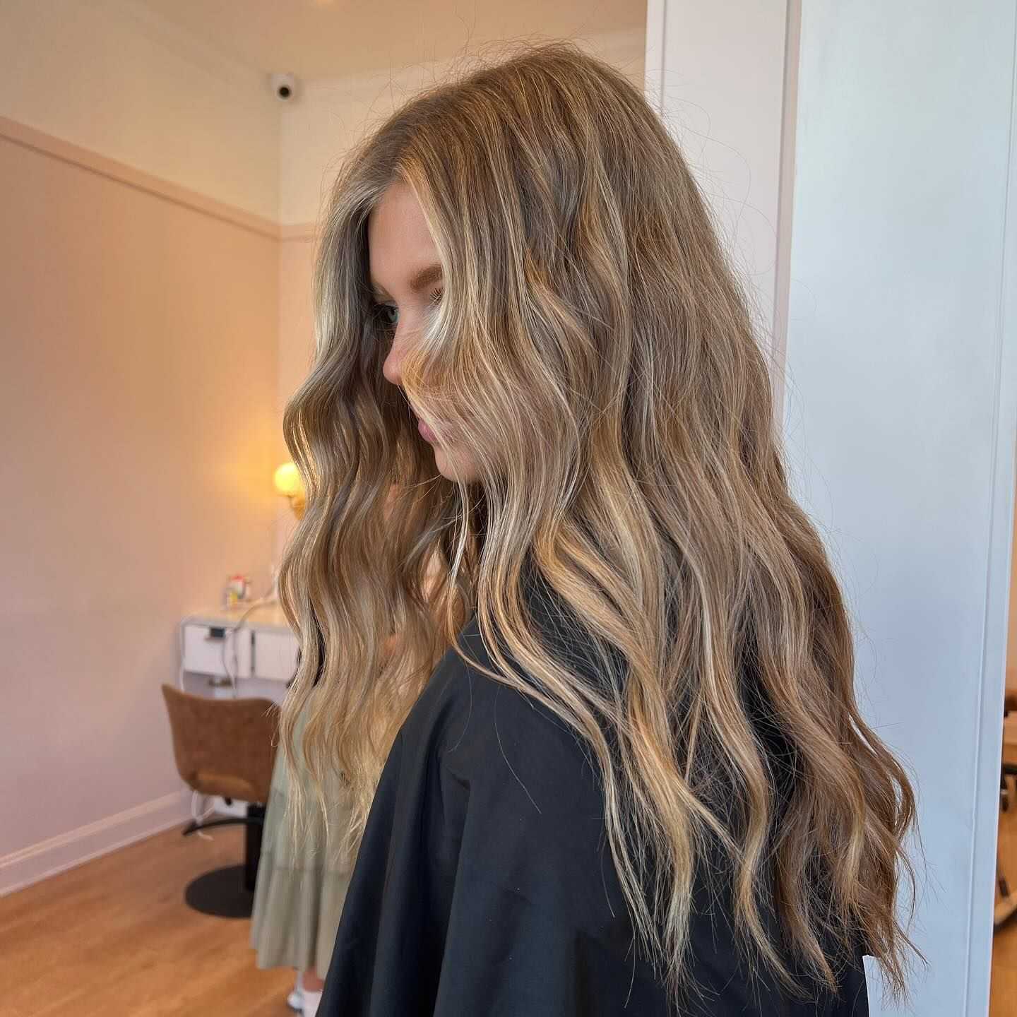 Long wavy blonde hair styled in a salon setting, showcasing a light, natural look.
