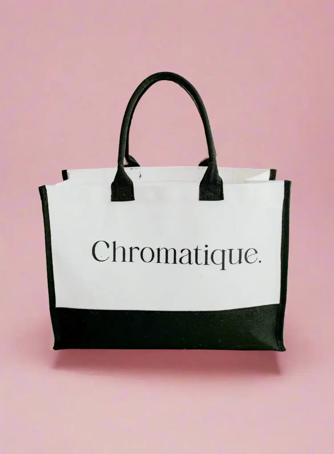 Black and white "Chromatique" tote bag against a pink background.