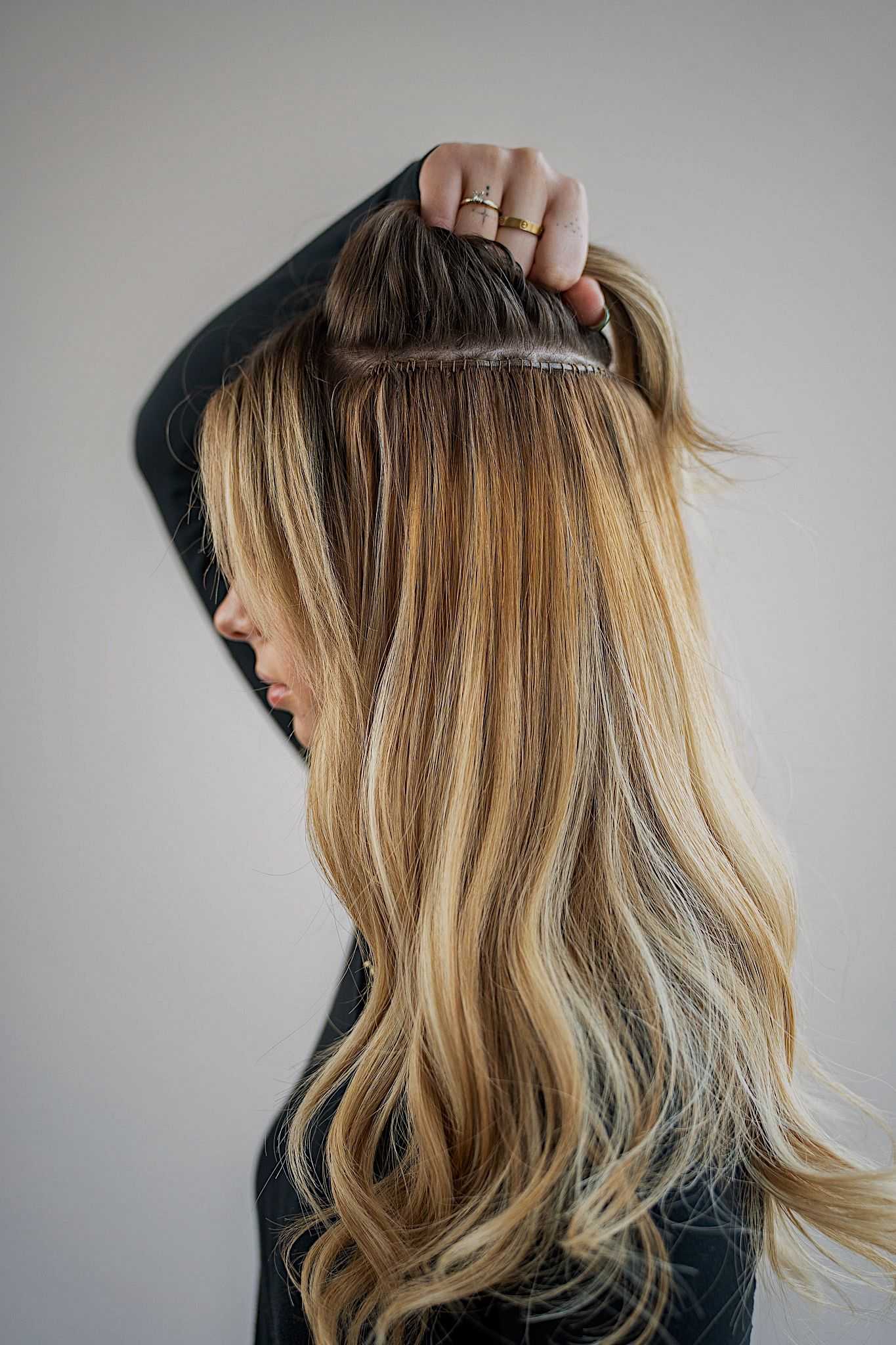 Person showing hair extensions in long, blonde hair.