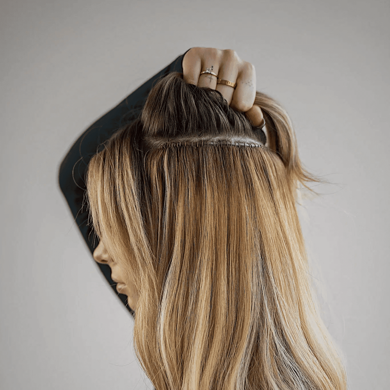 Person showing hair extensions in long, blonde hair.