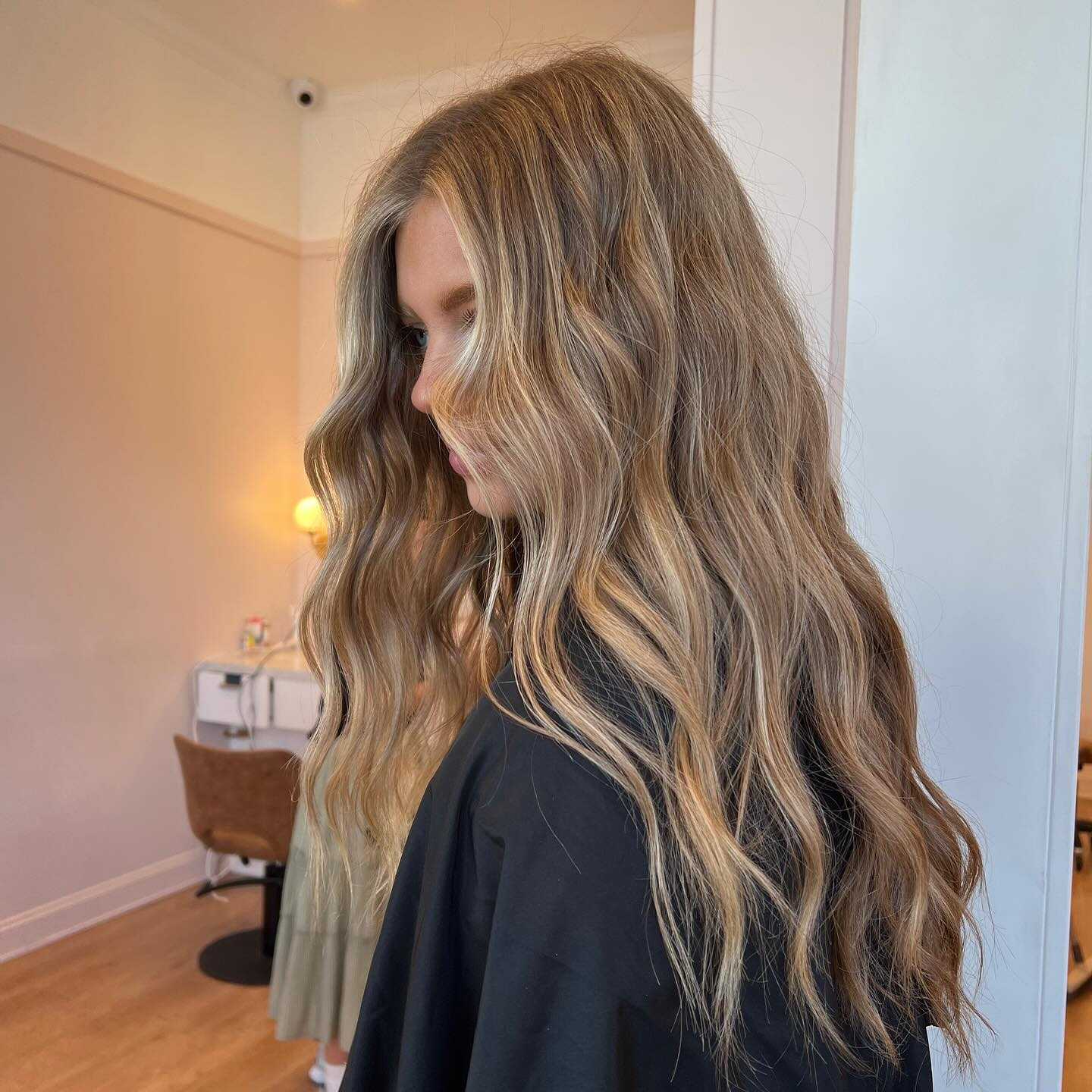 Long wavy blonde hair styled in a salon setting, showcasing a light, natural look.