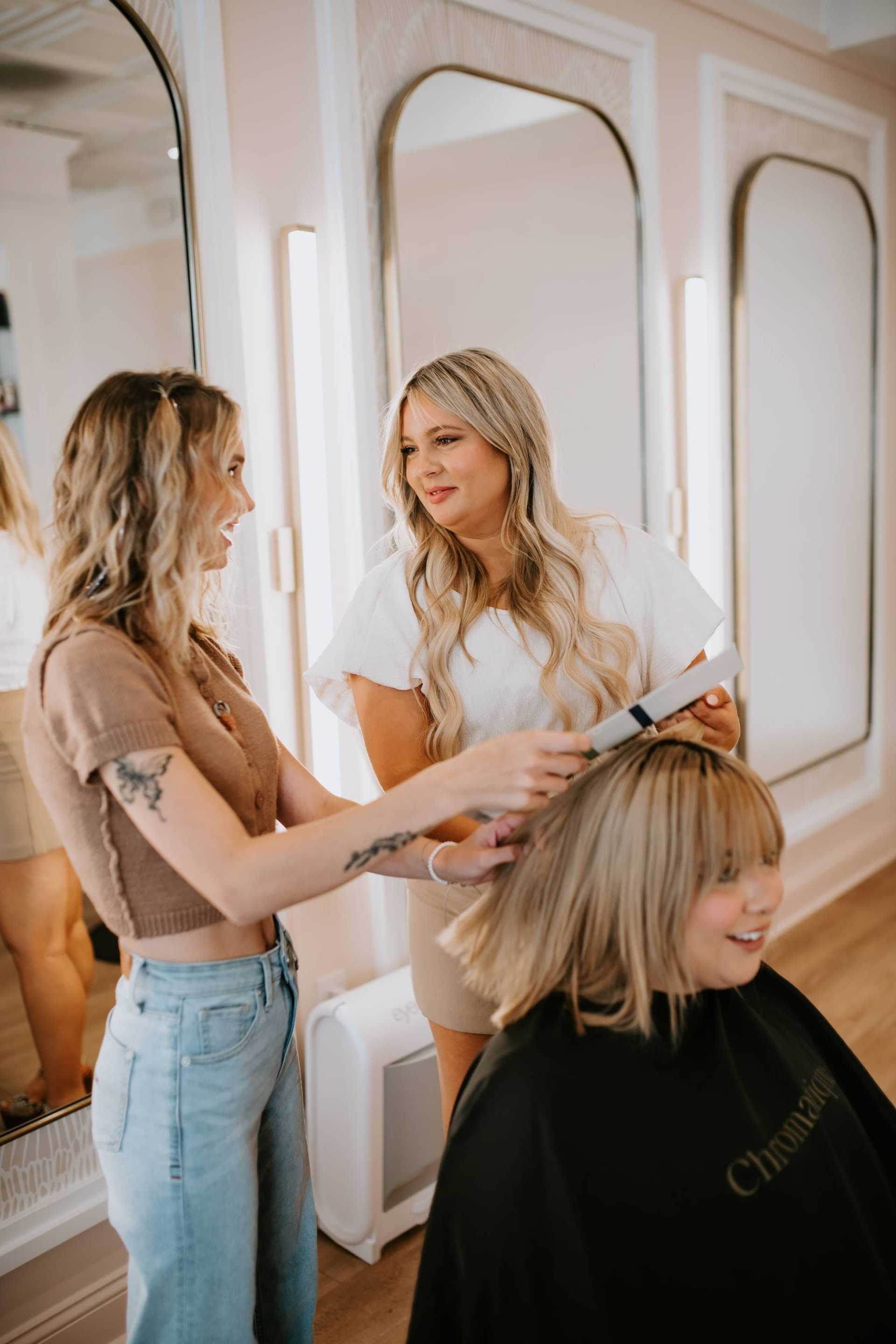 Two stylists with a client in a salon, discussing a haircut.
